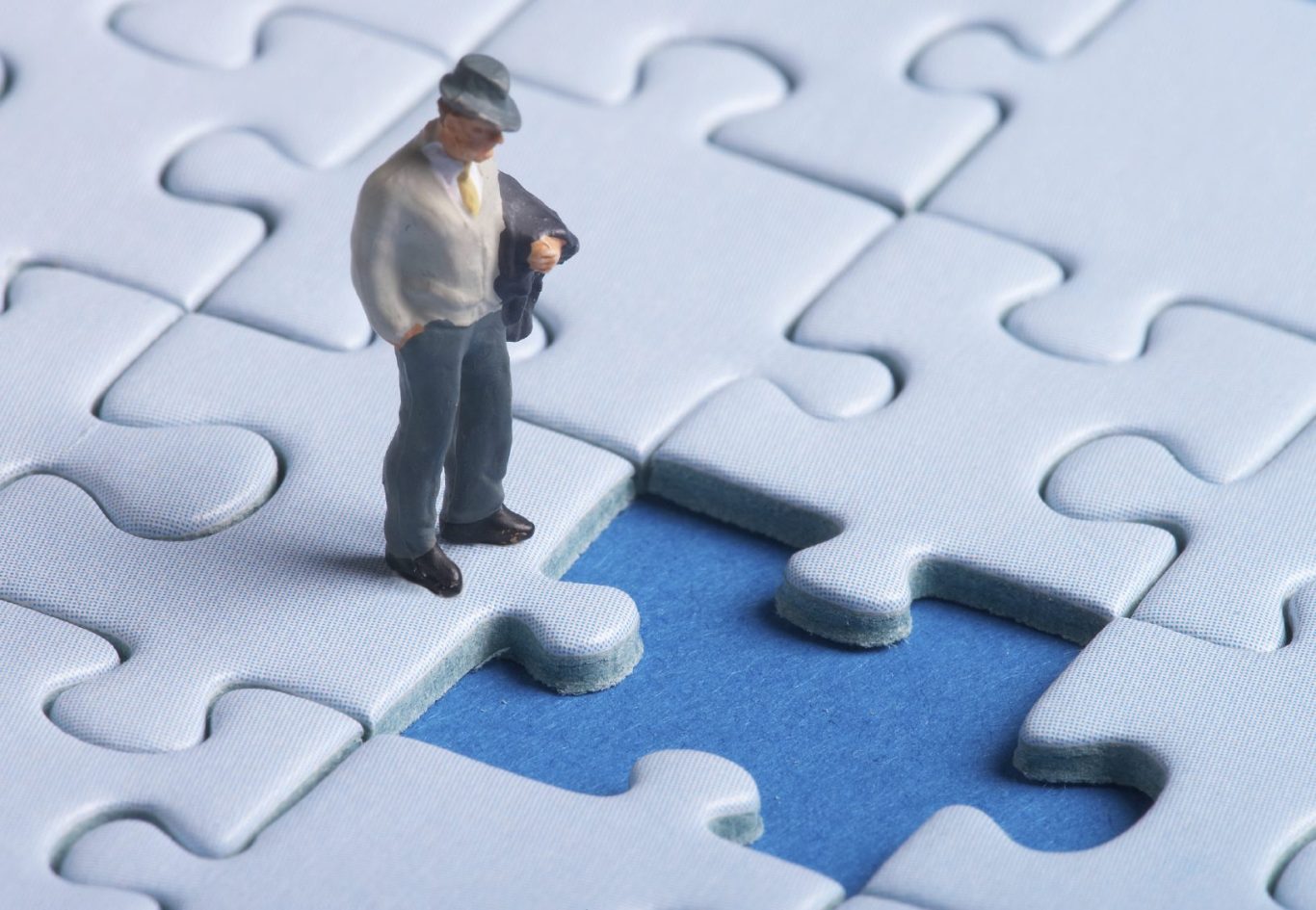 Therapie: Gemeinsam die fehlenden Teile Ihres Lebenspuzzles entdecken Mann betrachtet nachdenklich fehlendes Puzzlestück; symbolisiert, wie Therapie hilft, fehlende Lebenspuzzleteile zu finden und einzufügen